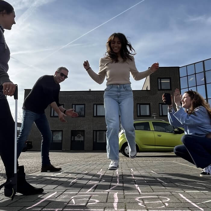 Een blije groep collga's aan het hinkelen met stoepkrijt